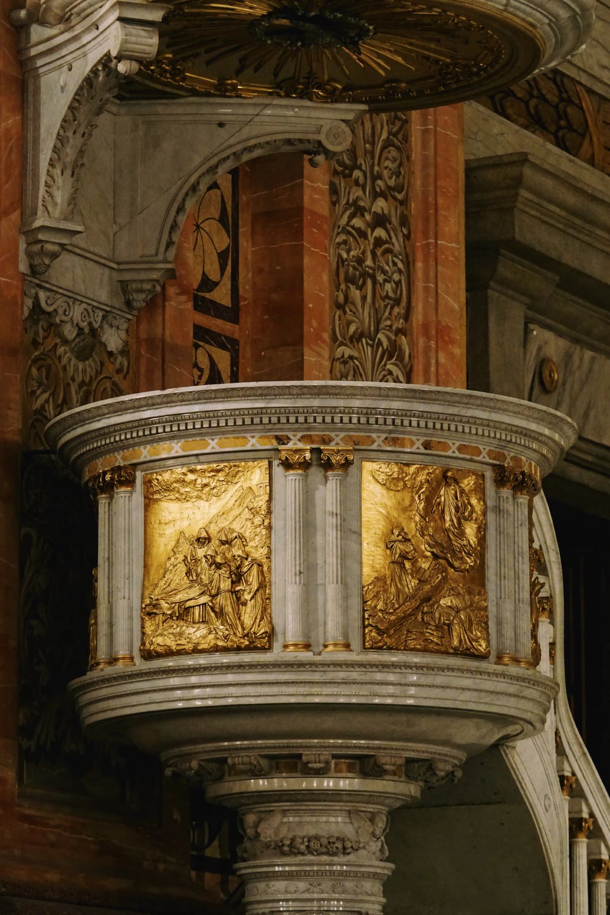 A baroque-style gilded pulpit with intricate golden reliefs and ornate marble columns.